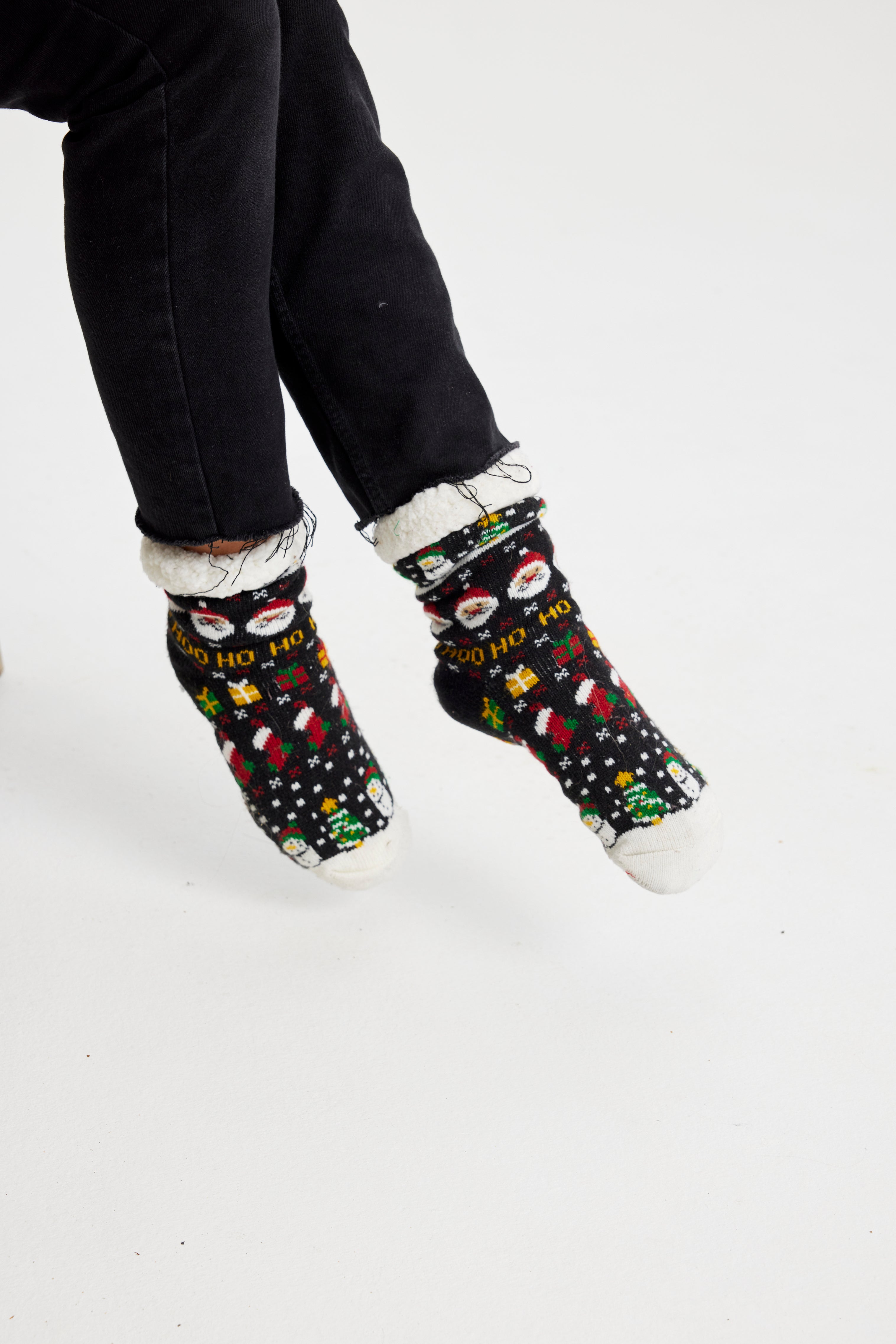 Een paar benen die zwarte kerstsokken dragen met een patroon erop.